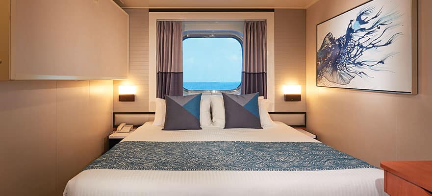 A bed with a window and a view of the ocean
Description automatically generated
