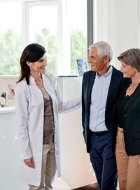 Couple receiving warm reception at a Widex Hearing Aid Centre by a female audiologist