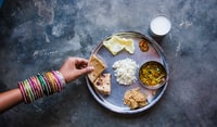 person holding stainless steel round tray with food 拿着带食物的不锈钢圆托盘的人