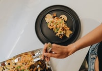 person holding black round plate with food 拿着带食物的黑色圆盘子的人