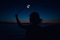 silhouette of woman holding sparkler during night time 夜间拿着火花的女人的轮廓