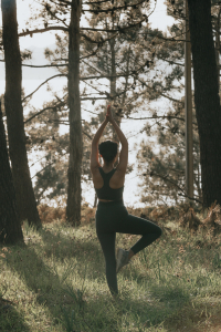 person does yoga pose outdoors surrounded by trees 人在户外摆瑜伽姿势，周围都是树木。