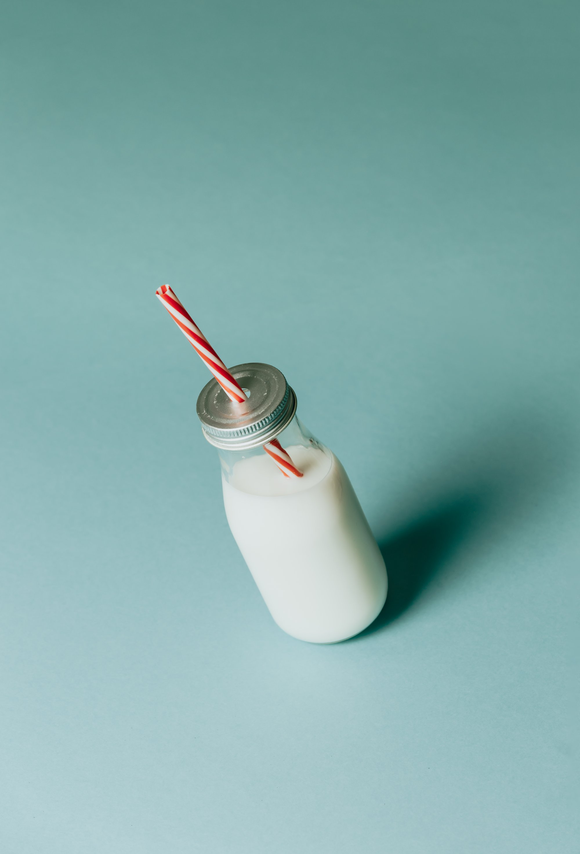 bottle of milk with silver lid and red striped straw 一瓶银色盖子和红条纹稻草的牛奶