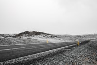 black asphalt road in the middle of snow covered field 黑色沥青路面在积雪覆盖的田野中间
