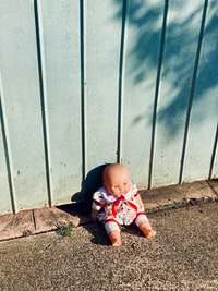 baby in white and red shirt and pants sitting on brown dirt 婴儿穿着白色和红色的衬衫和裤子坐在棕色的泥土上