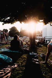 people sitting on green grass field during sunset 日落时人们坐在青草地上