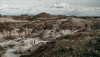 person in white shirt sitting on rock formation during daytime 白天穿着白色衬衫坐在岩层上的人