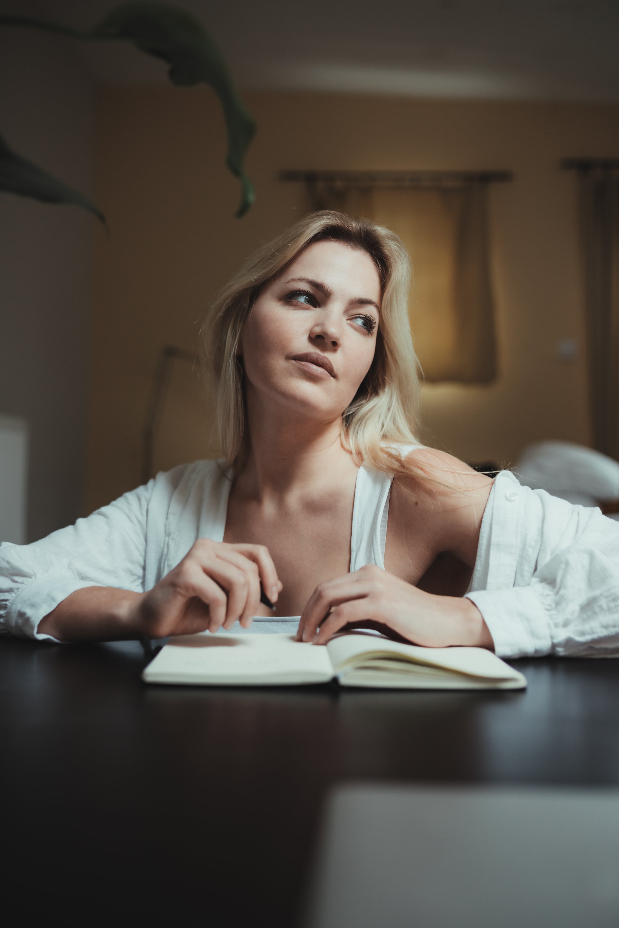 woman looks up in deep thought as she journals 女人在写日记时深思地抬起头来。