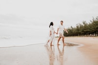 man and woman walking on white sand during daytime 白天，男人和女人在白沙上散步。
