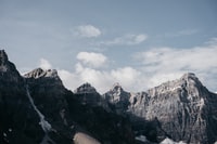 brown rocky mountain under white clouds during daytime 白云密布的褐色岩石山