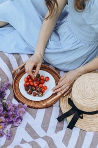 person holding brown round woven basket with red and orange fruits 拿着棕色圆形编织篮，红色和橙色水果的人