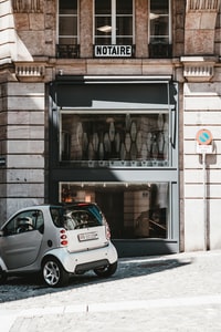 white 5 door hatchback parked beside brown brick building during daytime 白天停在棕色砖房旁边的白色5门掀背车