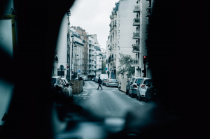 person walking across a car lined street in an urban setting 在城市环境中走过一条汽车两旁街道的人