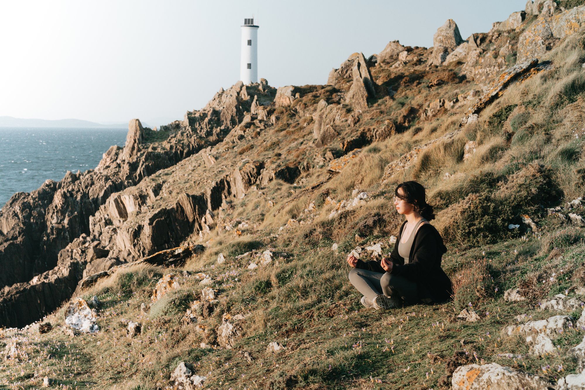 woman sits on the side of a hill above water 女人坐在水面上的一座小山边。