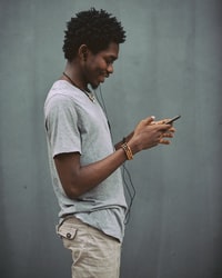 man in white crew neck t-shirt holding smartphone 身穿白色船员脖子的男子手持智能手机