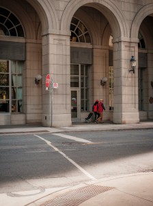 two people in red walk under a city building archway 两个穿红色衣服的人在一座城市建筑的拱门下行走。