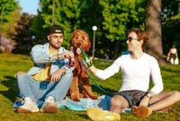 man and woman sitting on green grass field holding brown bear plush toy during daytime 白天，男人和女人坐在青草地上拿着棕熊毛绒玩具。