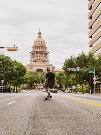 man riding bicycle on road near brown concrete building during daytime 白天，男子在棕色混凝土建筑物附近的道路上骑自行车。