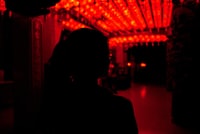 silhouette of woman standing near red and yellow string lights during night time 夜间站在红灯和黄灯旁的女人的轮廓