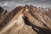 brown rocky mountain under blue sky during daytime 白天蓝天下褐色的岩石山