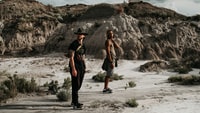man in black tank top and black pants standing on gray sand during daytime 白天穿着黑色背心和黑色裤子站在灰色沙滩上的男人
