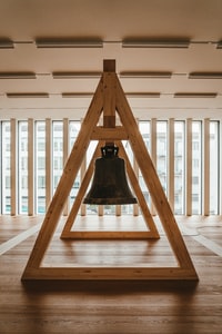 black bell on brown wooden stand 棕色木架上的黑色钟