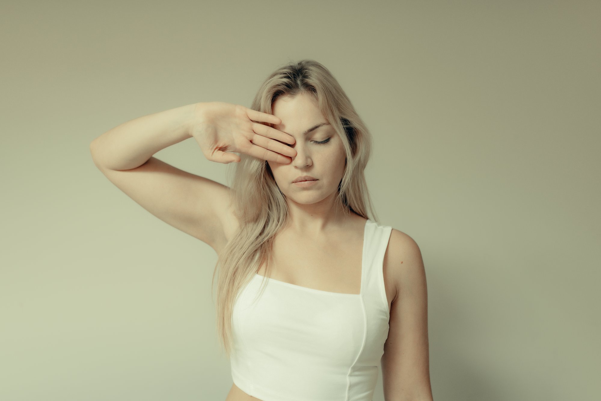 woman holds her arm up and covers her left eye 女人举起她的手臂，遮住她的左眼。