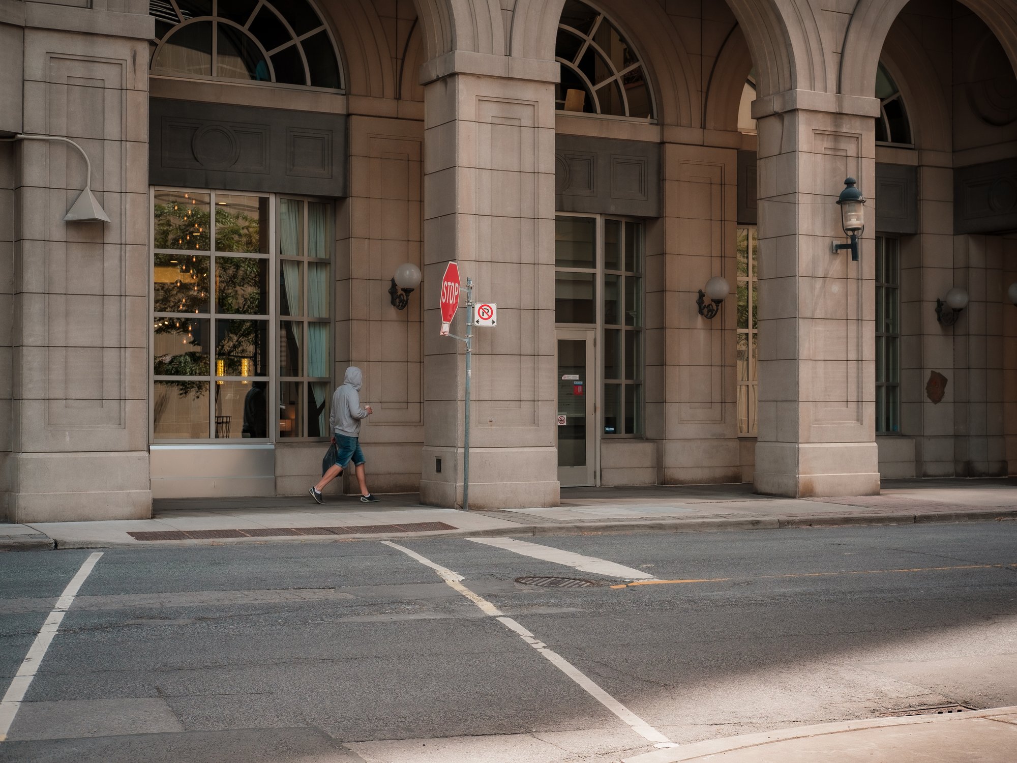 person walking under a city building with tall archways 在高拱的城市建筑下行走的人