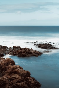 brown rocky shore with blue ocean water during daytime