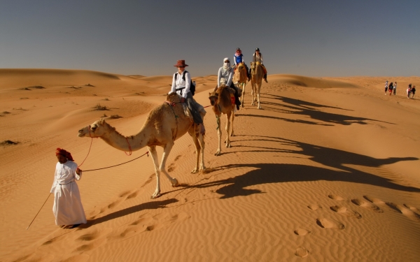 tourists riding camels at Wahiba sands