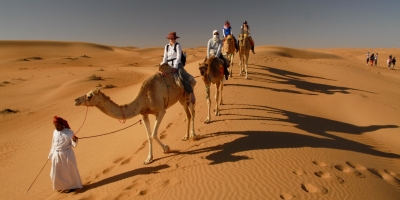 tourists riding camels at Wahiba sands