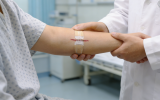 The doctor is checking the patient's wound which is closed by the butterfly stitches